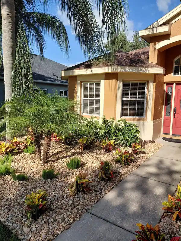 Vibrant front yard landscape design in Sanford FL with tropical plants and decorative rock