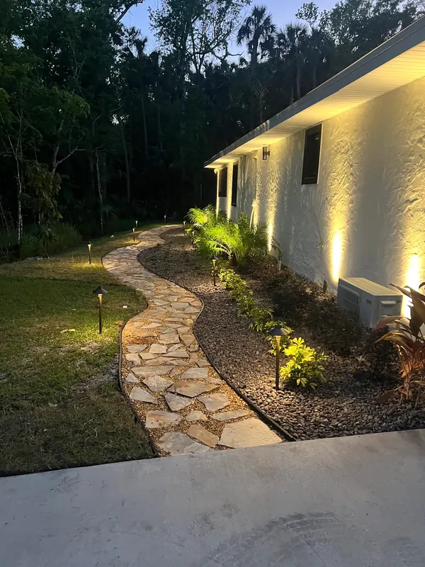 Nighttime view of a custom flagstone walkway and decorative rock beds in Daytona Beach