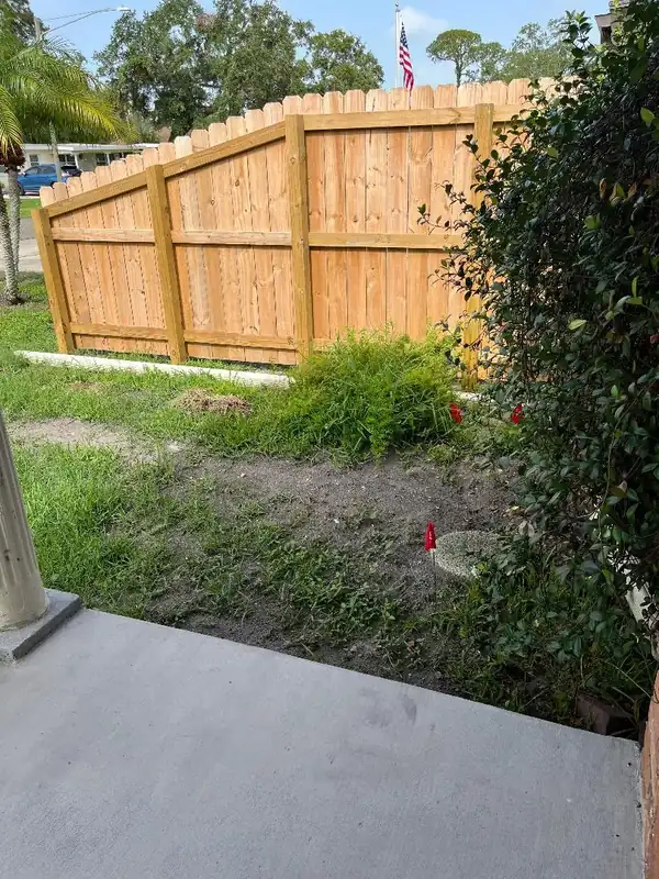 New drain line installation beside a wooden fence in a St. Petersburg yard